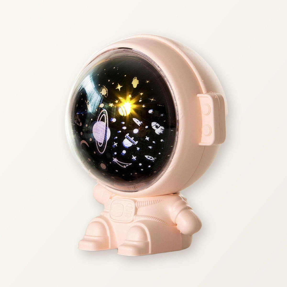 Pink astronaut star projector with its visor lit on a plain cream background
