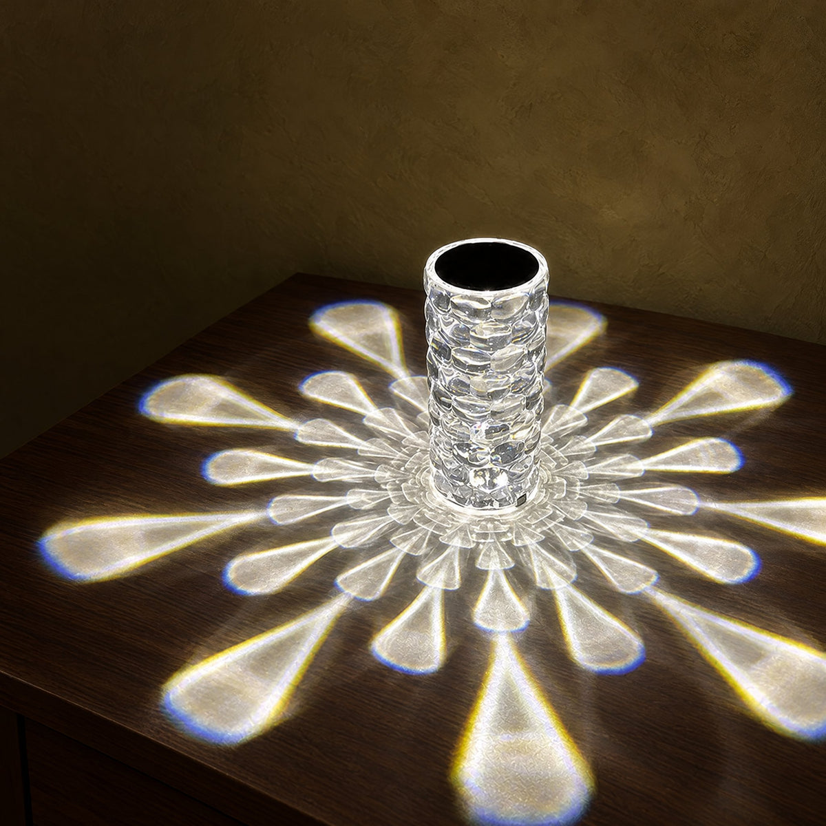 Crystal-look acrylic lamp casting a starburst of white droplet-shaped light on a dark bedside table