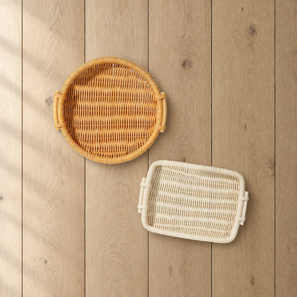 Round honey and rectangular natural rattan trays on a light oak table, seen from above