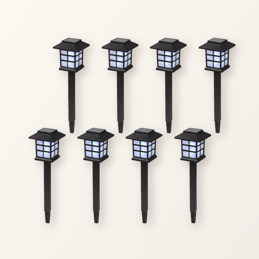 Eight black pagoda-style solar path lanterns on ground stakes, in two rows on a plain cream background