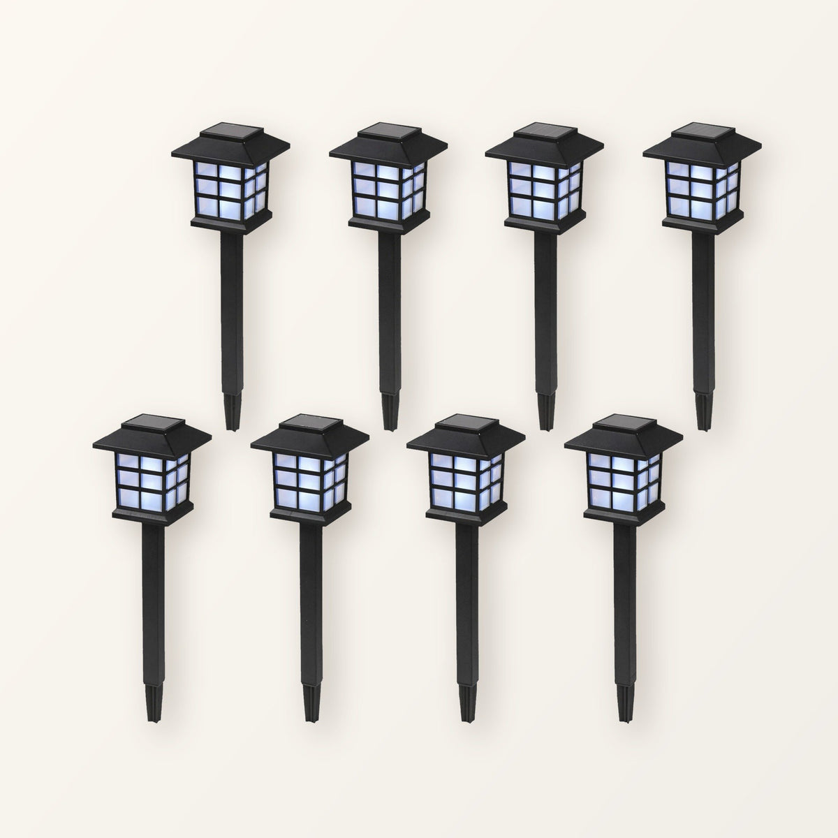 Eight black pagoda-style solar path lanterns on ground stakes, in two rows on a plain cream background