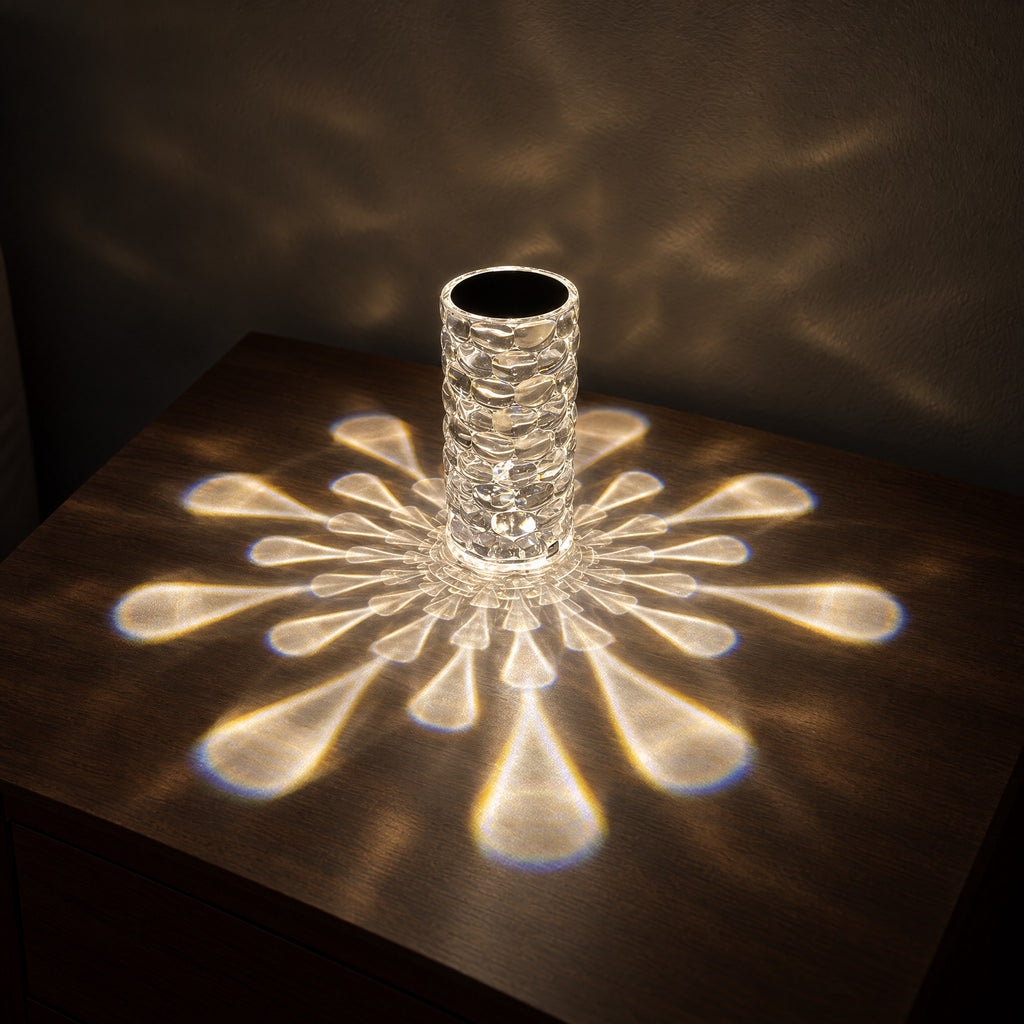 Crystal-look acrylic lamp casting a starburst of warm white droplet-shaped light across a walnut bedside table at night