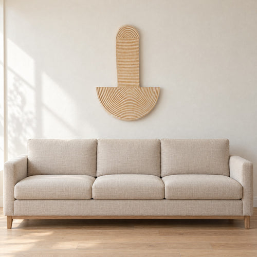 Abstract Wall Mask 3 hung on a warm white wall above a plain oatmeal linen sofa